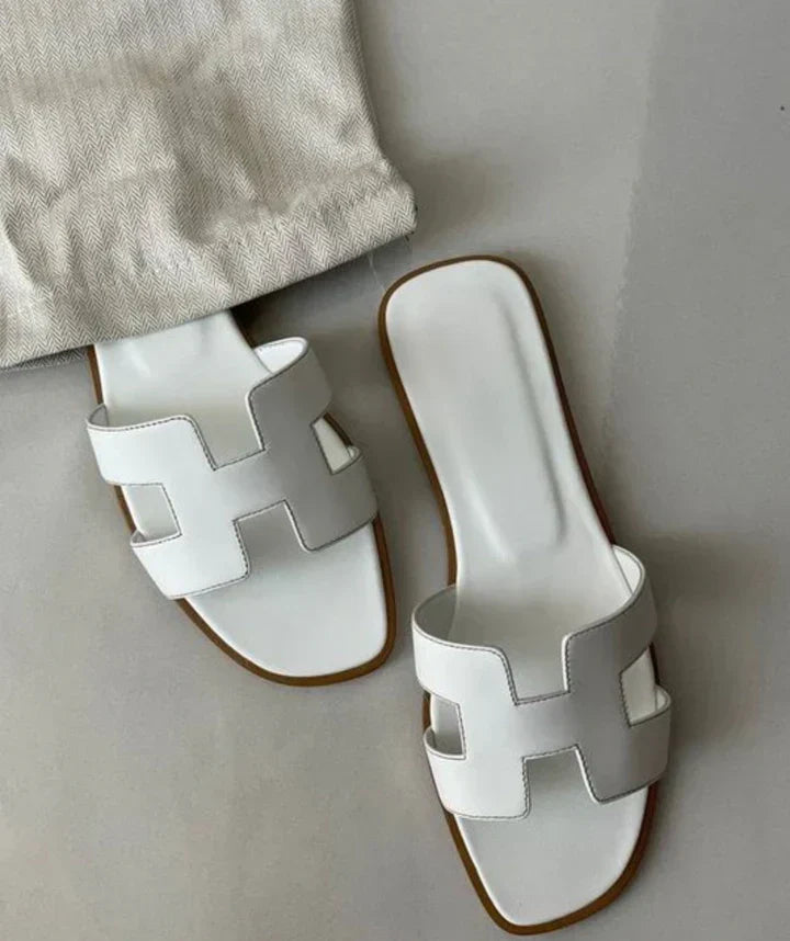 StrapMaven | Sandali in pelle moderni con design a H Perché amerai i nostri sandali: Stile a infilare: Pratici da indossare quotidianamente, senza compromettere l'eleganza. Finitura curata: Realizzazione artigianale con dettagli delicati per un risultato premium. Cuoio vegan di alta qualità: Morbido al tatto, rispettoso degli animali e durevole. Tacco di 2 cm: Un'altezza ideale per sottolineare la silhouette assicurando comfort.