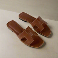 H Sandals Donna: Eleganza Estiva in Pelle PU Adotta uno stile estivo raffinato con i nostri H Sandals, mules dal design iconico che combinano comfort ed eleganza in modo semplice. La loro silhouette essenziale si integra perfettamente con qualsiasi outfit, ideale per una giornata in città o una serata in terrazza. Questi sandali slip-on donna, perfetti come sandali estivi donna, sono una scelta indispensabile per chi ama le calzature estive donna pratiche e alla moda.