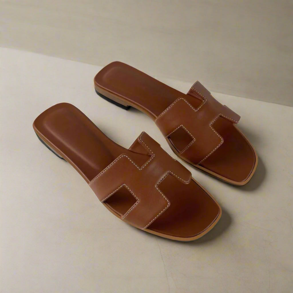 H Sandals Donna: Eleganza Estiva in Pelle PU Adotta uno stile estivo raffinato con i nostri H Sandals, mules dal design iconico che combinano comfort ed eleganza in modo semplice. La loro silhouette essenziale si integra perfettamente con qualsiasi outfit, ideale per una giornata in città o una serata in terrazza. Questi sandali slip-on donna, perfetti come sandali estivi donna, sono una scelta indispensabile per chi ama le calzature estive donna pratiche e alla moda.
